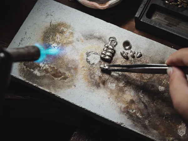 Groepje deelnemers aan een sieraden workshop, geconcentreerd aan het werk